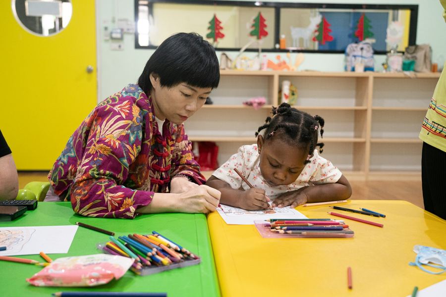 An adult and a child drawing together at a table