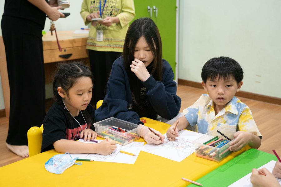 Young pupils drawing together at a classroom table