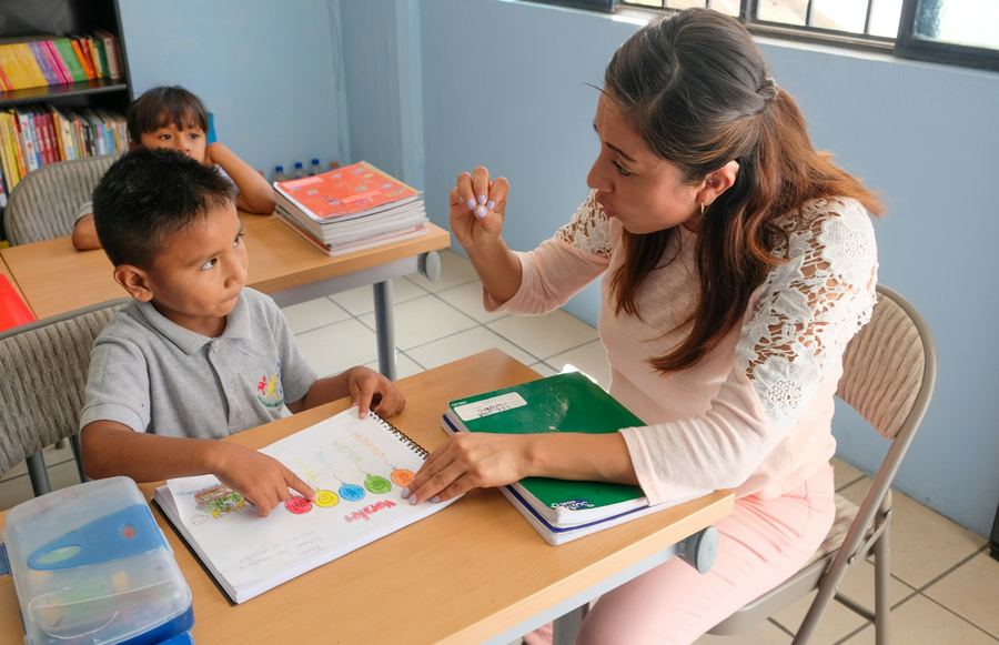A teacher supporting a pupil with a workbook in a specialist classroom