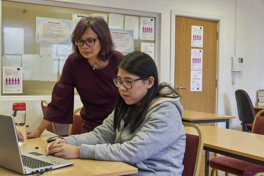 An educator helping a student on a laptop