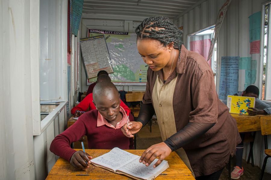 A teacher supporting a pupil with their writing